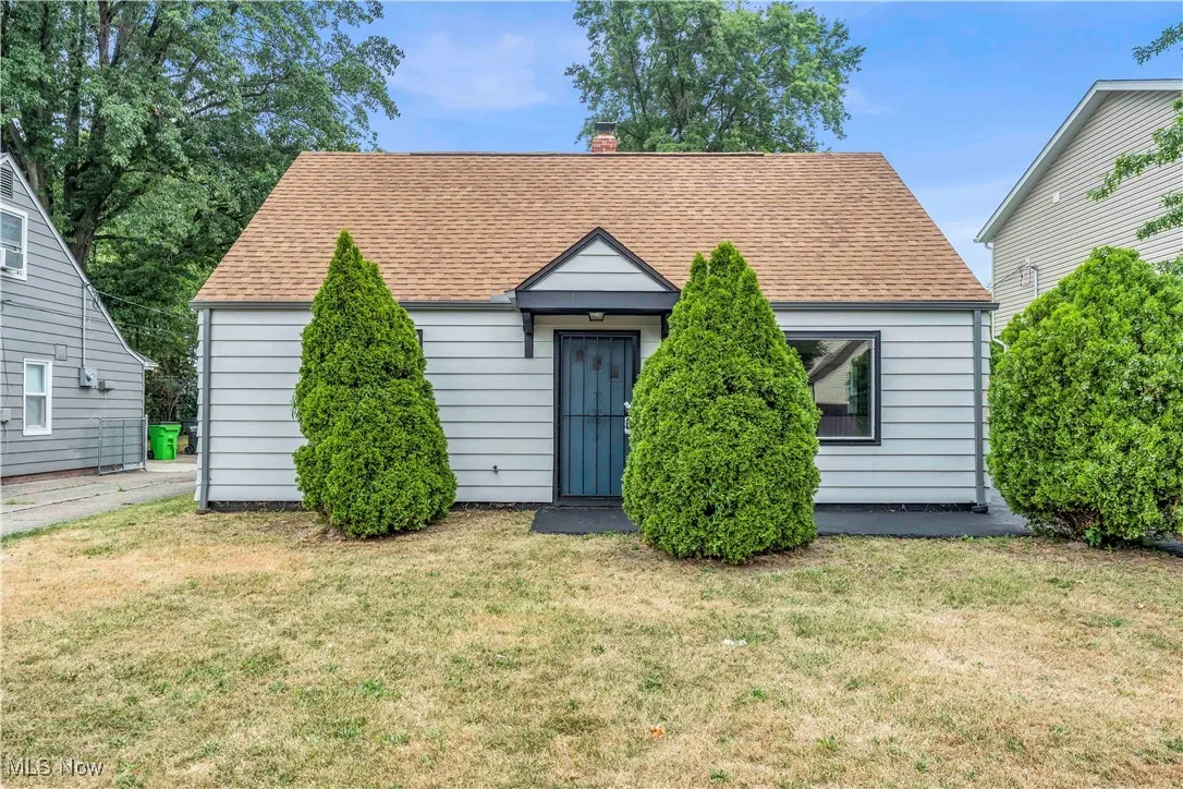View of front of home with a front yard, a chimney, and roof with shingles