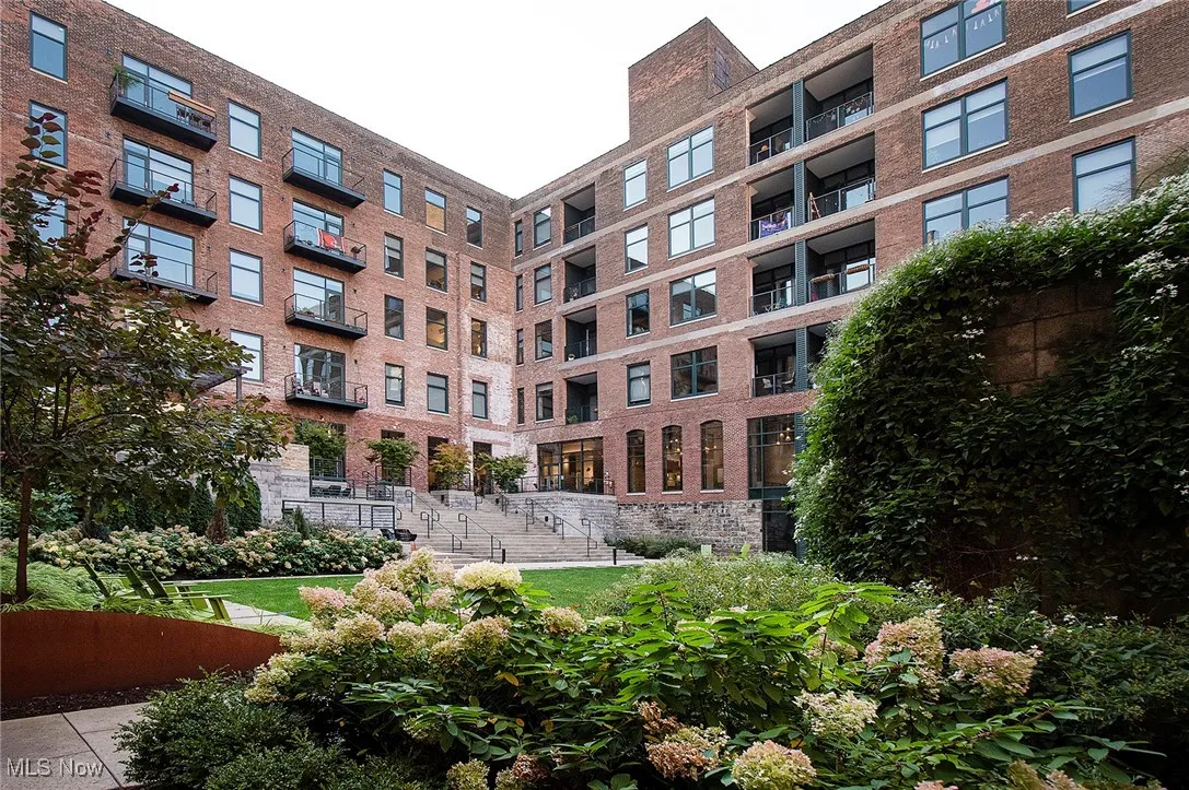 View of apartment building and complex featuring an internal courtyard with mature landscaping
