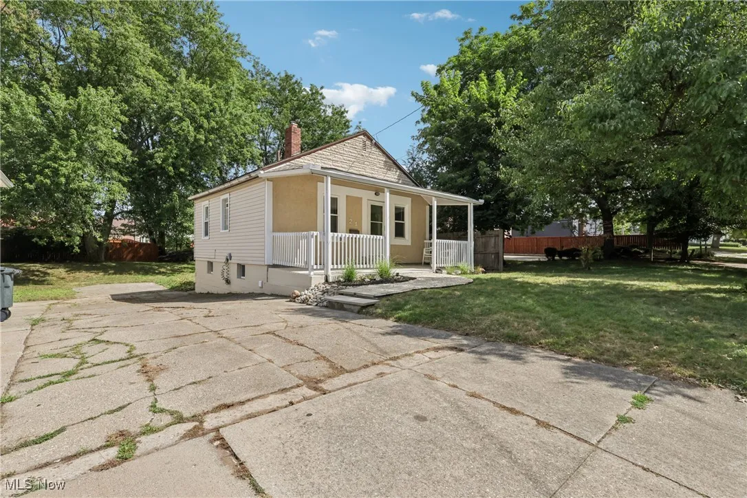 Front / side view of the property showing a porch, driveway and yard