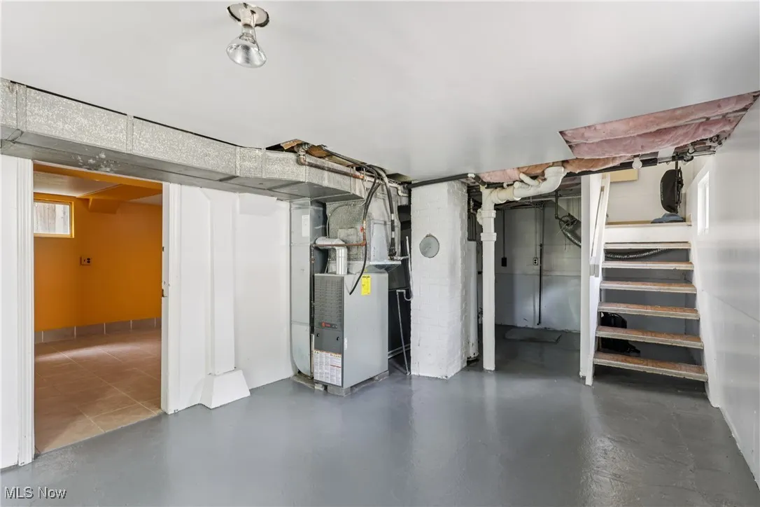 Basement featuring heating unit and stairs