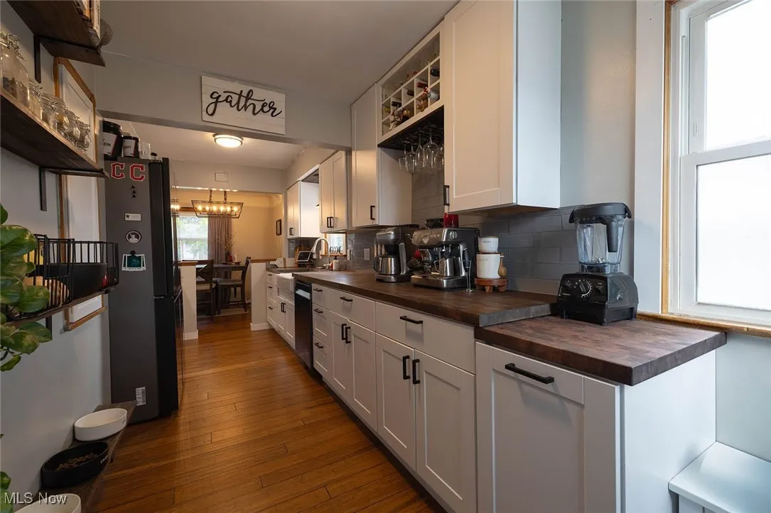 Kitchen featuring wooden counters, white cabinets, wood flooring, stainless steel appliances, and decorative backsplash