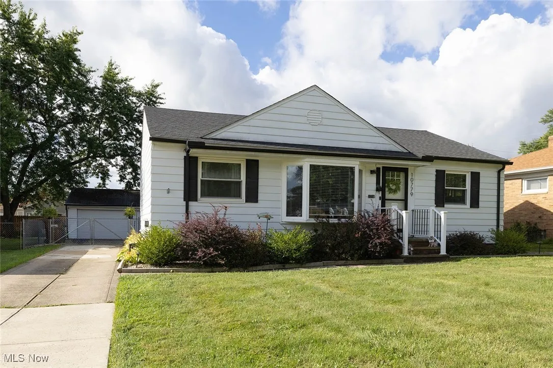 Bungalow-style house featuring an outdoor structure, a shingled roof, and concrete driveway