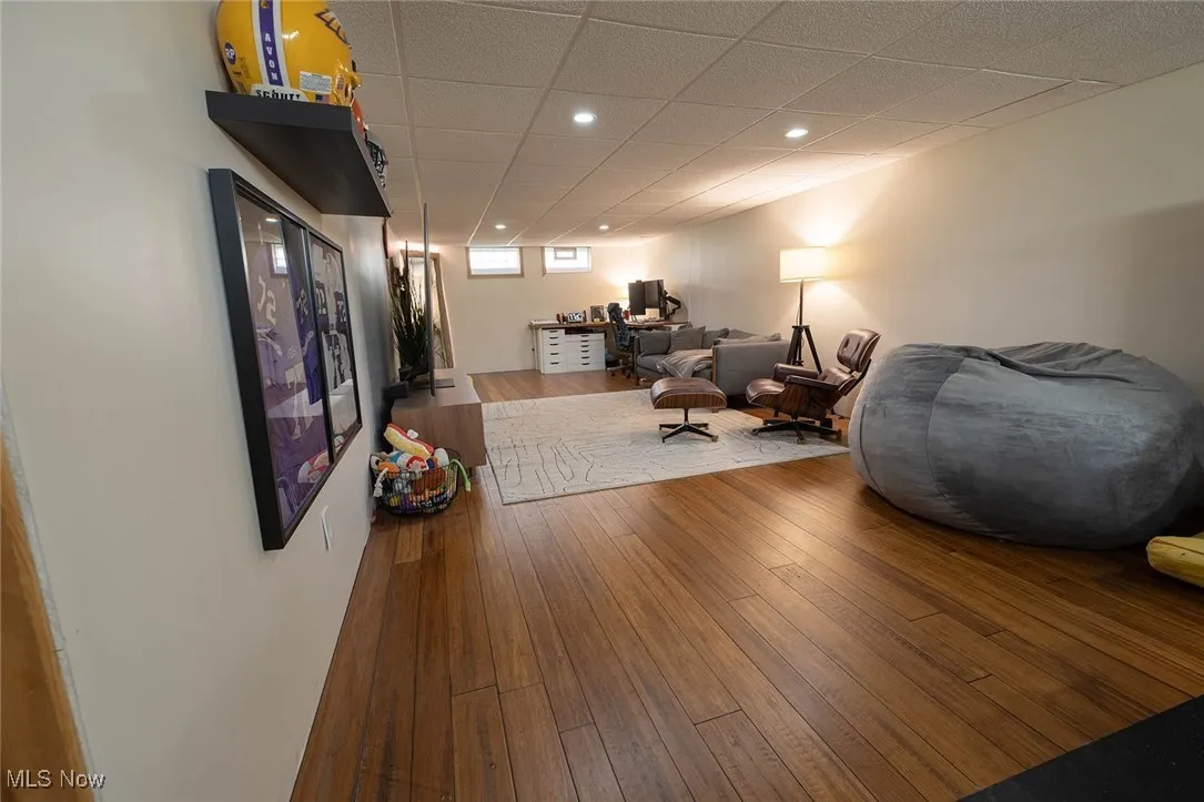 Living room featuring wood-type flooring, a drop ceiling, and an office area