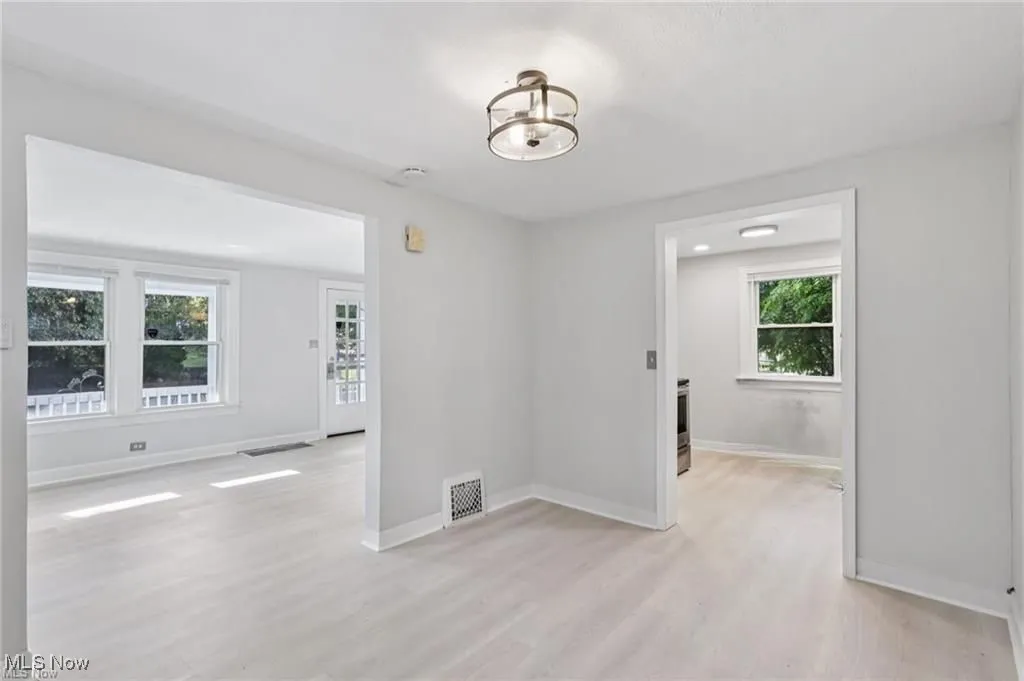 Unfurnished room with light wood-type flooring and a chandelier