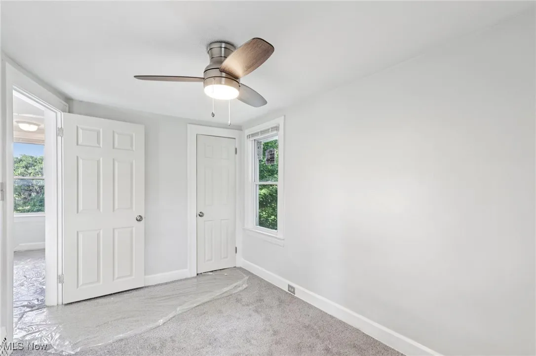 Unfurnished bedroom with carpet floors, multiple windows, and ceiling fan