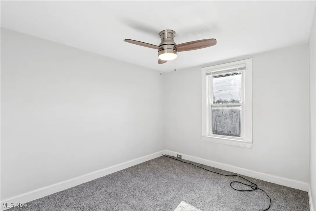 Carpeted empty room featuring baseboards and ceiling fan