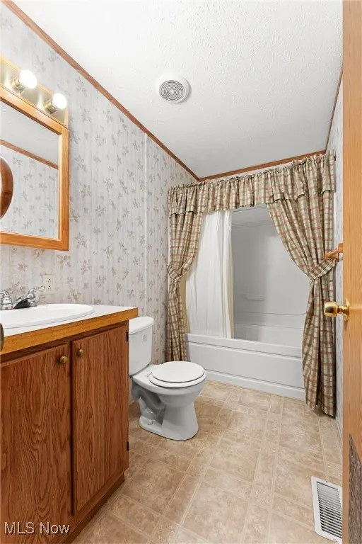 Bathroom with shower / tub combo with curtain, vanity, crown molding, and a textured ceiling