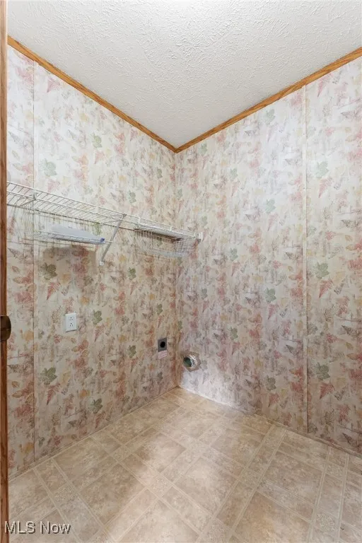 Bathroom featuring a textured ceiling, wallpapered walls, and crown molding