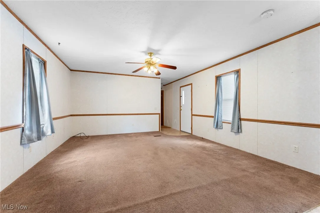 Spare room featuring ornamental molding, carpet flooring, and ceiling fan