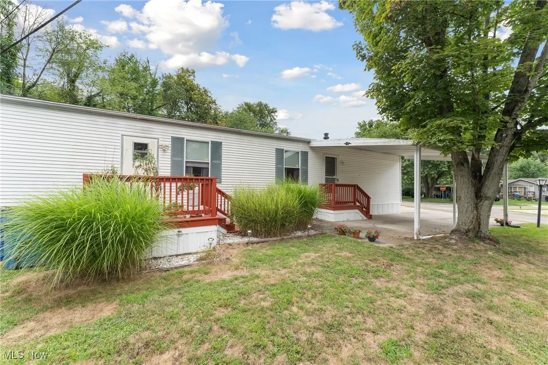 Back of property with an attached carport and a yard