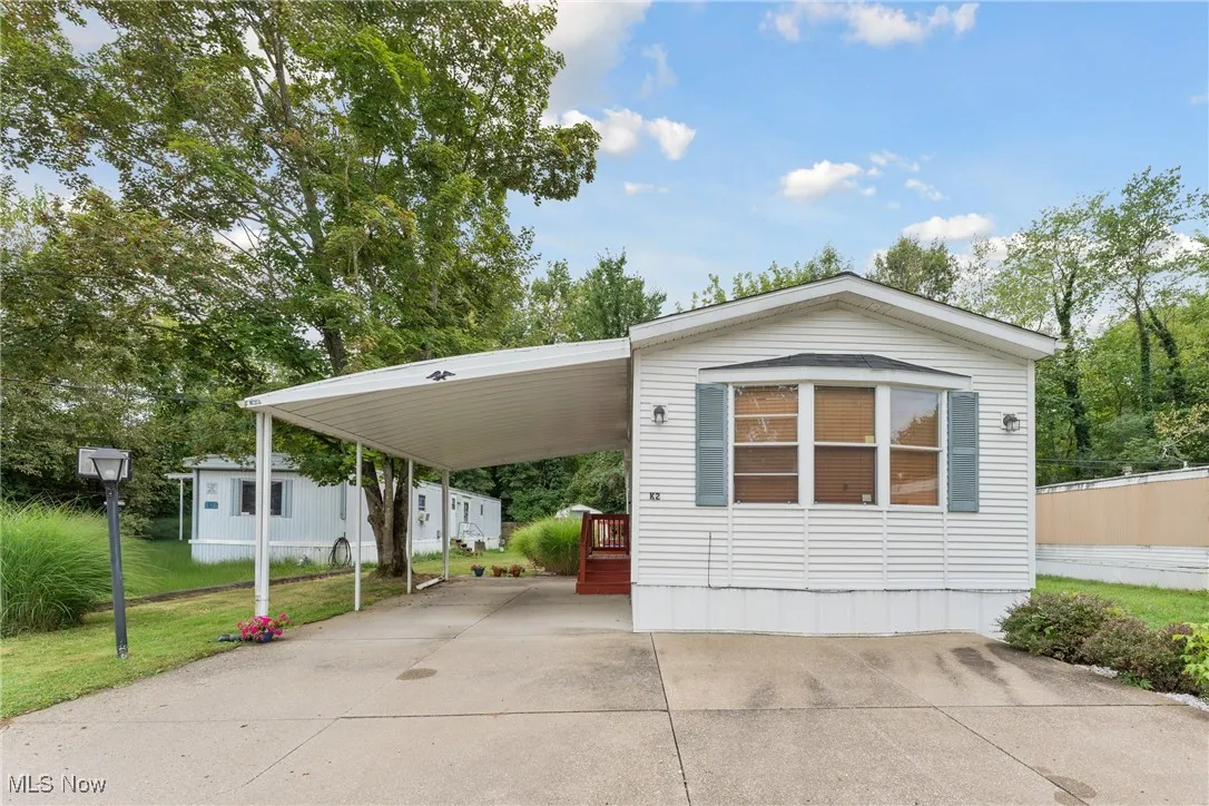 Manufactured / mobile home with driveway, a carport, and a front lawn