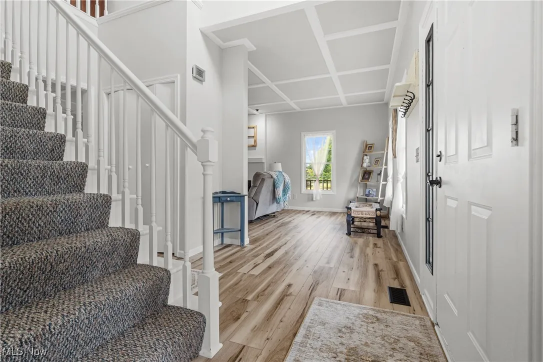 Entrance foyer with stairs, coffered ceiling, and light wood-type flooring