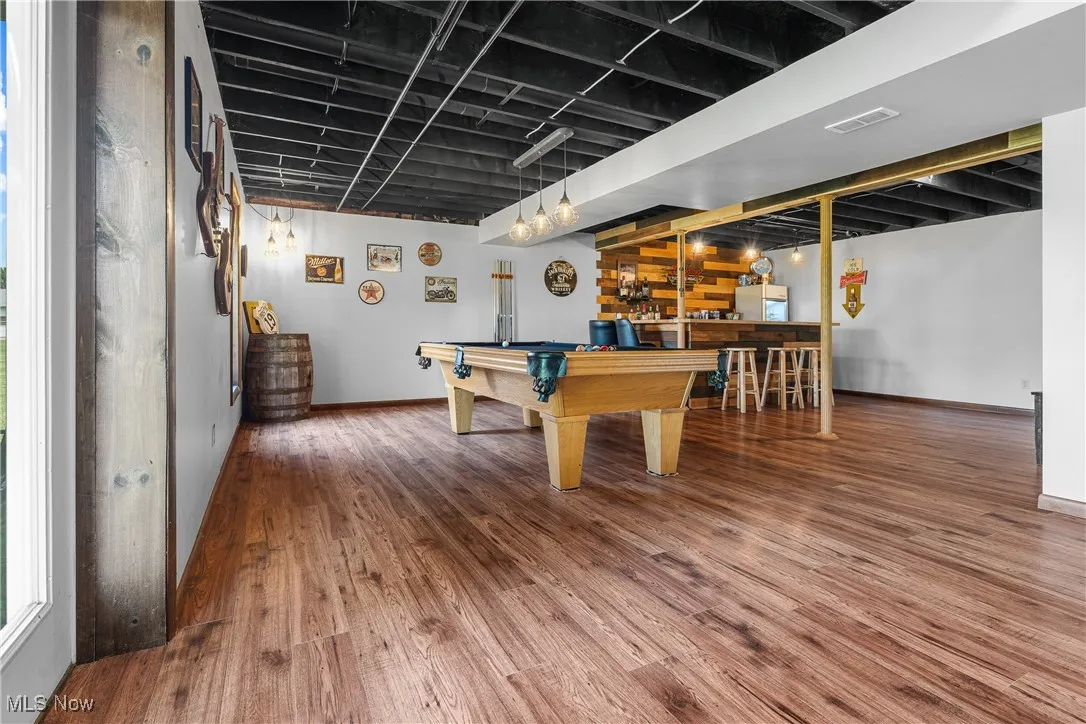 Recreation room featuring wood finished floors, bar, billiards table, and plenty of natural light