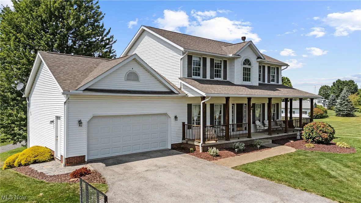 View of front facade featuring a porch, a front lawn, driveway, and a shingled roof