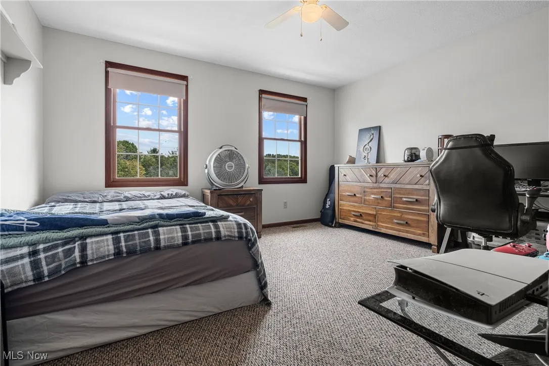 Bedroom with light carpet, an office area, and ceiling fan