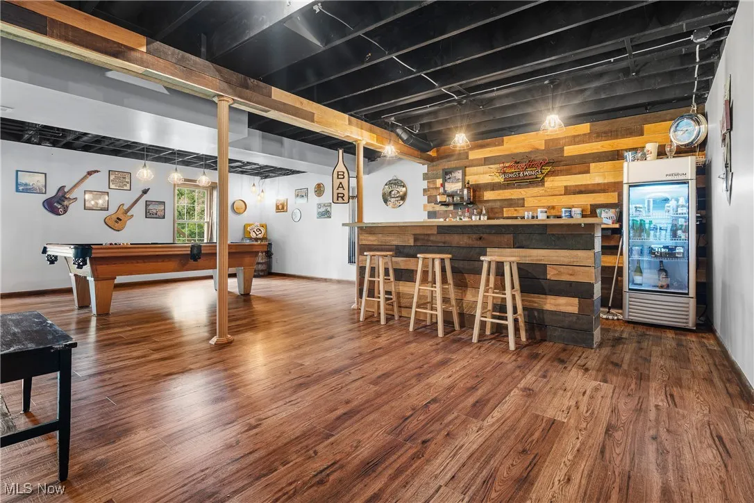 Below grade area with a bar, wood finished floors, billiards table, and wood walls