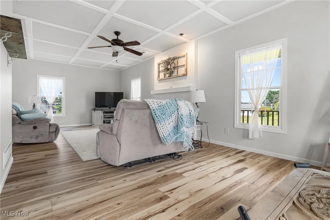 Living room featuring healthy amount of natural light, coffered ceiling, wood finished floors, and a ceiling fan