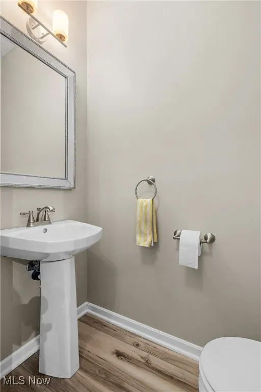 Half bath with baseboards and wood finished floors
