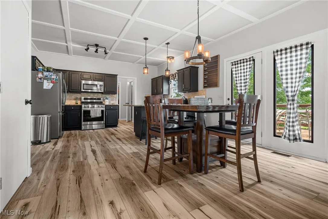 Dining area with light wood finished floors and coffered ceiling