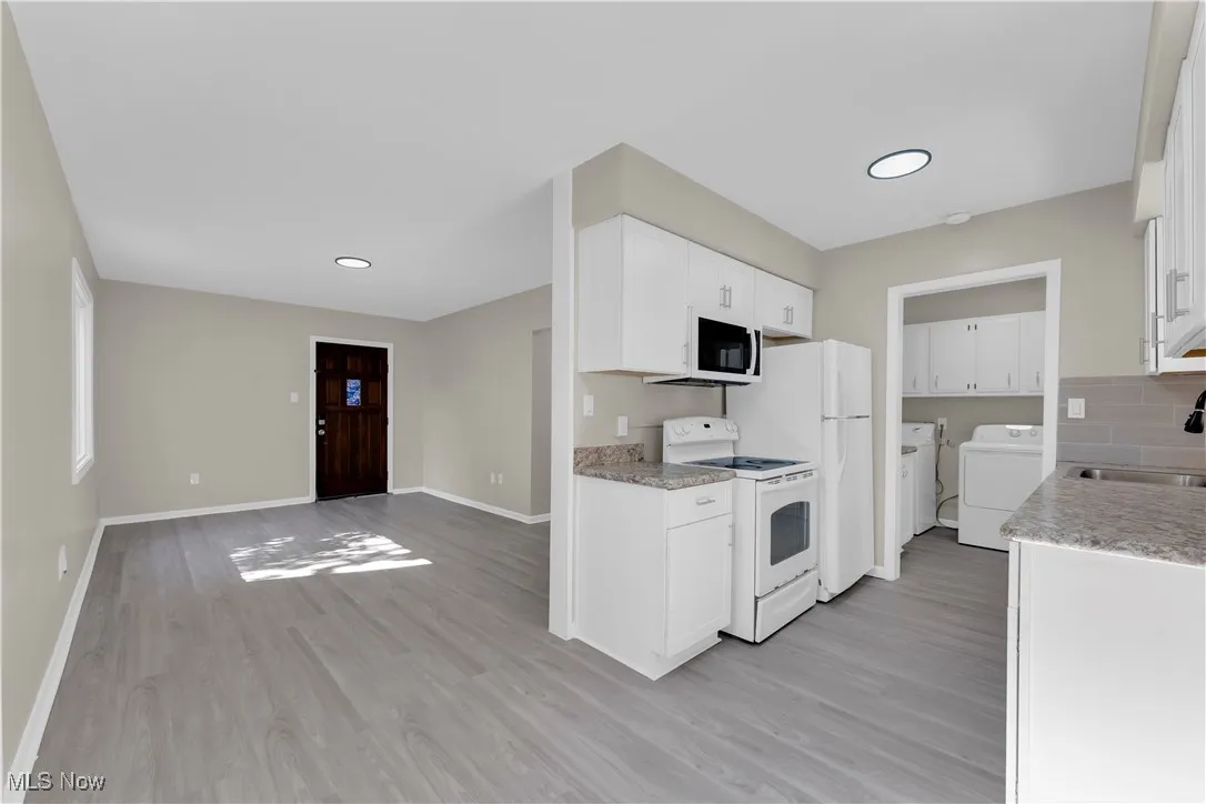 Kitchen featuring light countertops, white appliances, light wood-style floors, white cabinets, and recessed lighting