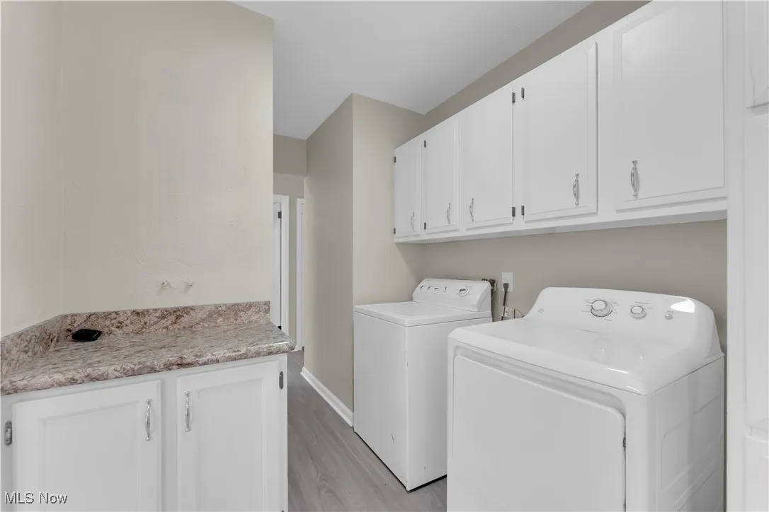Laundry room with cabinet space, light wood-type flooring, and washing machine and clothes dryer