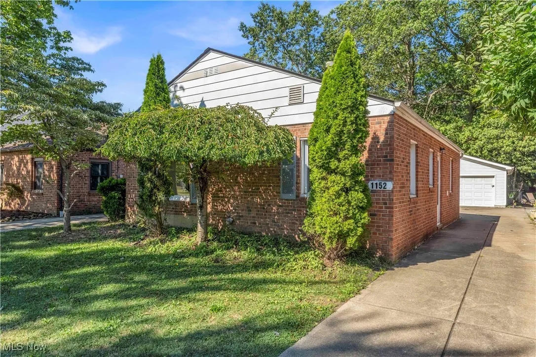 View of home's exterior with brick siding, a garage, a yard, and an outdoor structure