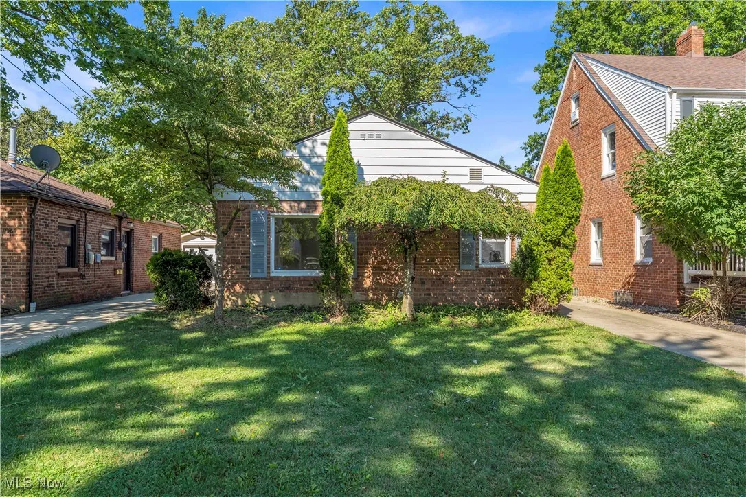 Bungalow-style home featuring brick siding, a front yard, and a patio area