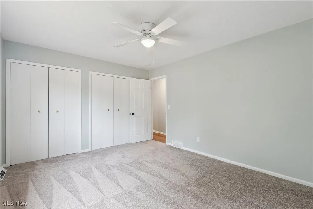 Unfurnished bedroom featuring two closets, carpet flooring, and ceiling fan