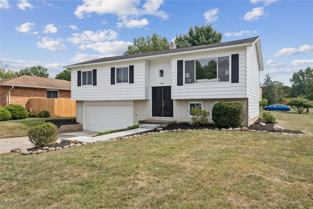 Bi-level home featuring brick siding, an attached garage, concrete driveway, and a chimney
