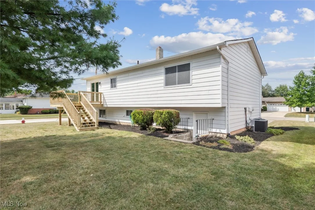 Back of property featuring stairway, a lawn, a chimney, and a wooden deck