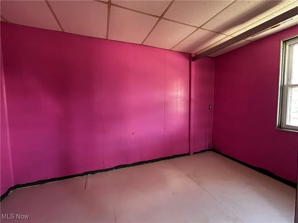 Unfurnished room with a paneled ceiling and concrete flooring