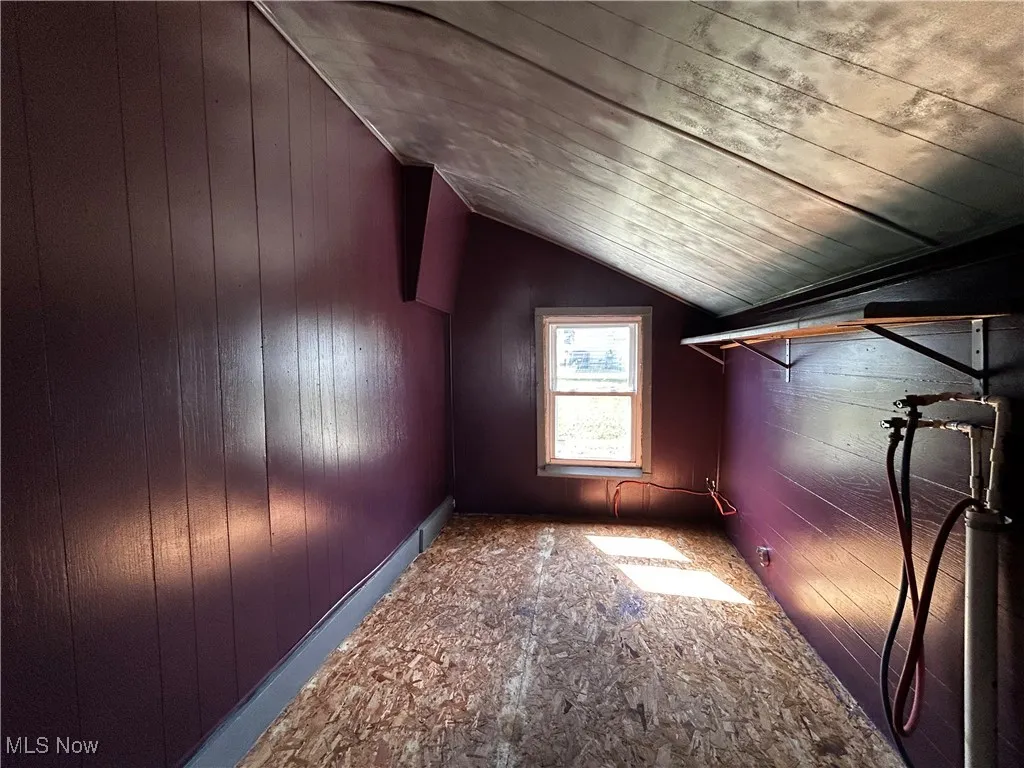 Bonus room with wooden walls and vaulted ceiling