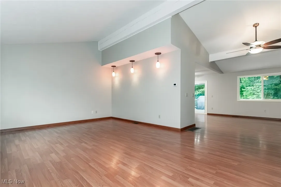 Unfurnished room featuring vaulted ceiling, light wood-style flooring, and a ceiling fan