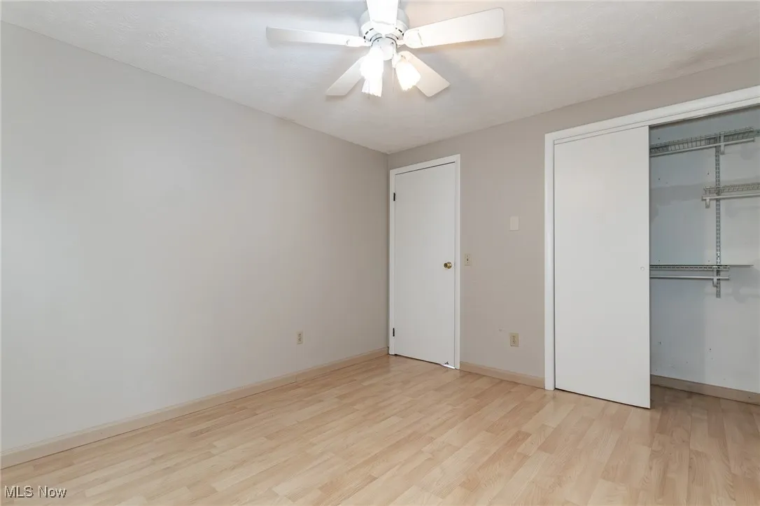 Unfurnished bedroom featuring light wood finished floors, a closet, ceiling fan, and a textured ceiling