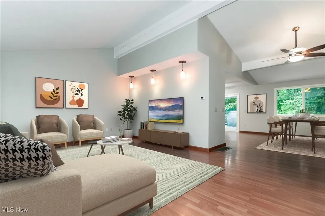 Living room with lofted ceiling, ceiling fan, and wood finished floors