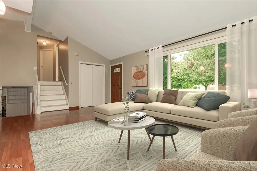 Living area featuring stairway, lofted ceiling, and wood finished floors