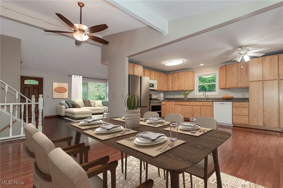 Dining area featuring a ceiling fan, beamed ceiling, dark wood-type flooring, and stairway