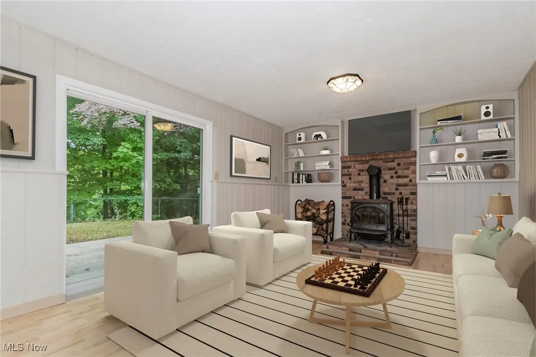 Living area with a wood stove, wood finished floors, and built in features