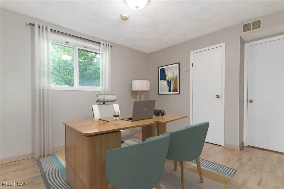 Home office with light wood finished floors and a textured ceiling