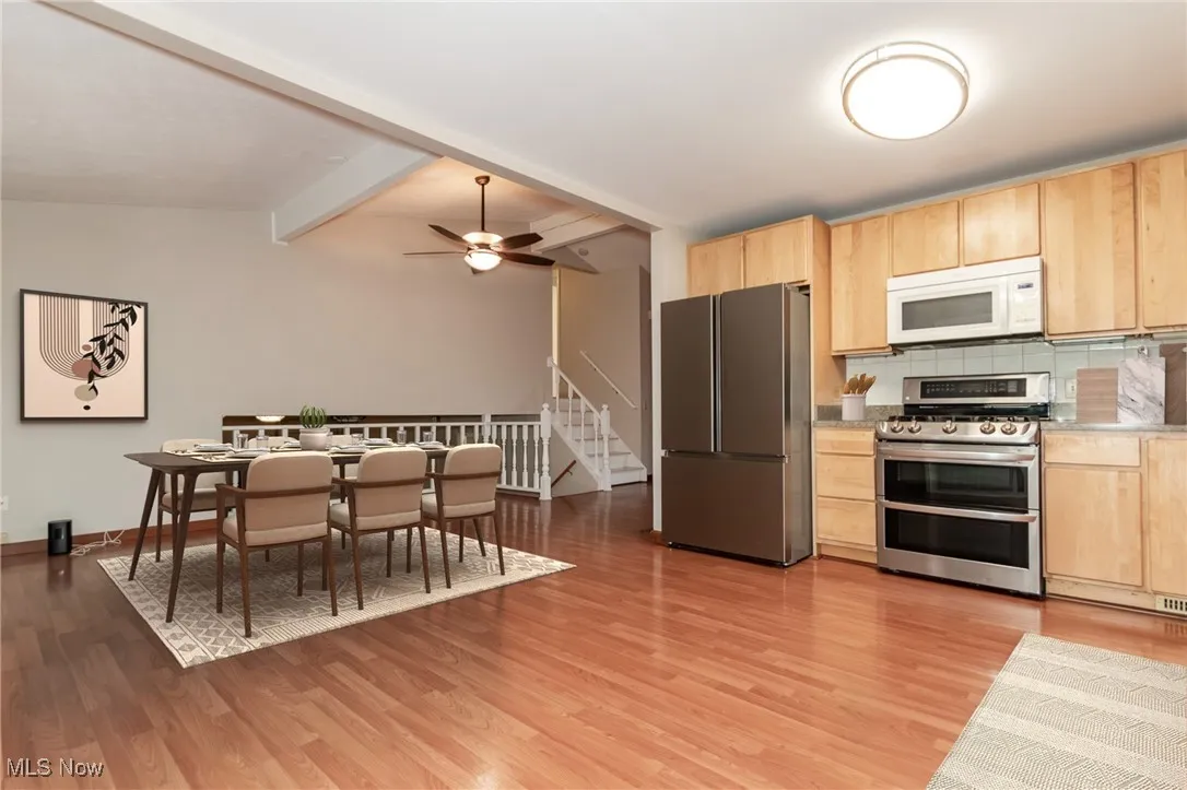 Kitchen featuring light brown cabinetry, stainless steel appliances, tasteful backsplash, and light wood-style flooring