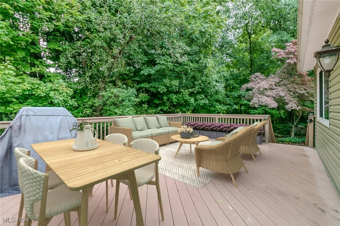 Deck featuring an outdoor living space, area for grilling, and view of wooded area