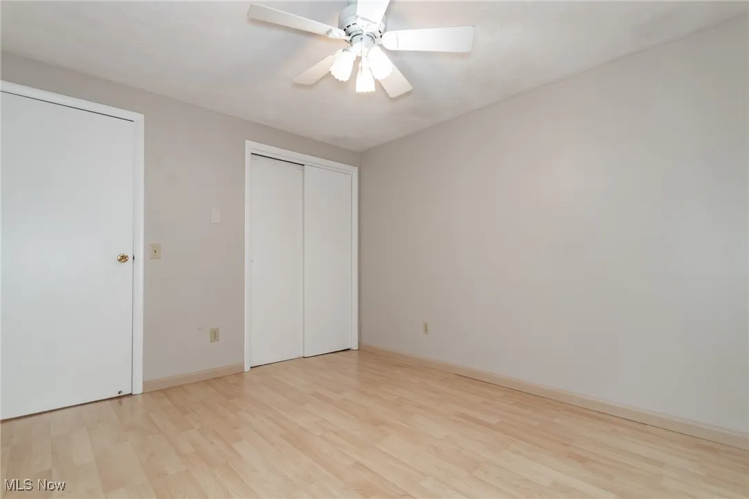 Unfurnished bedroom with light wood-style floors, ceiling fan, and a closet