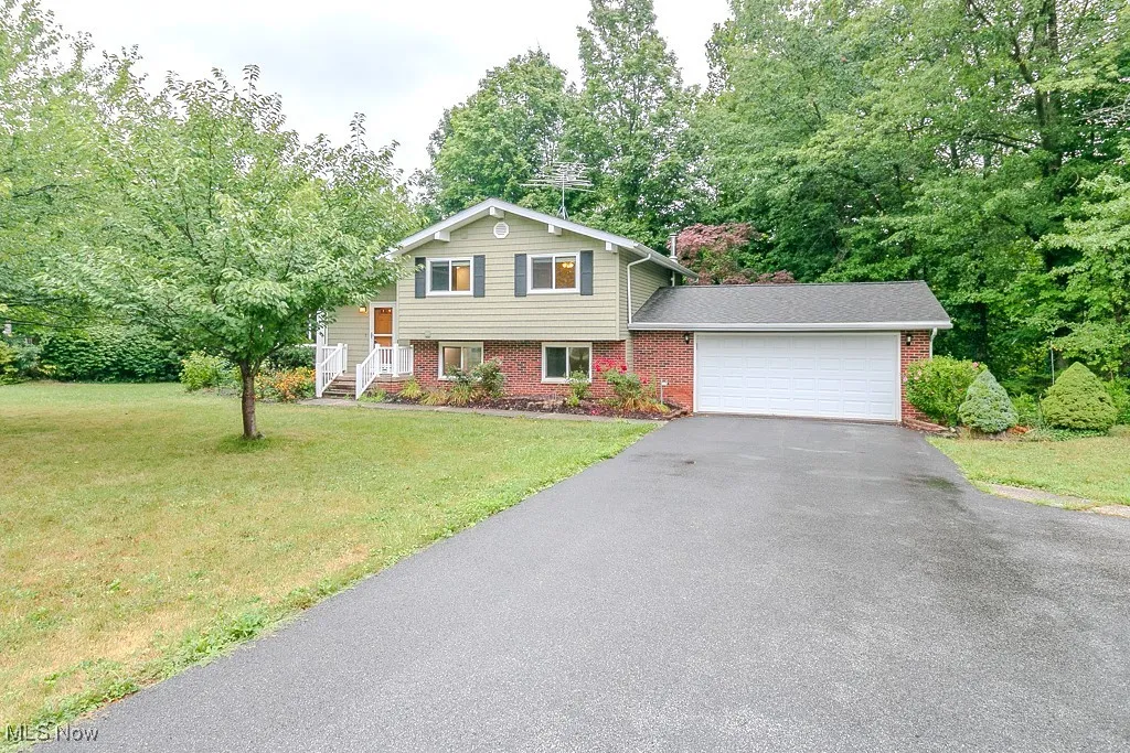 Tri-level home featuring brick siding, a garage, driveway, and a front yard