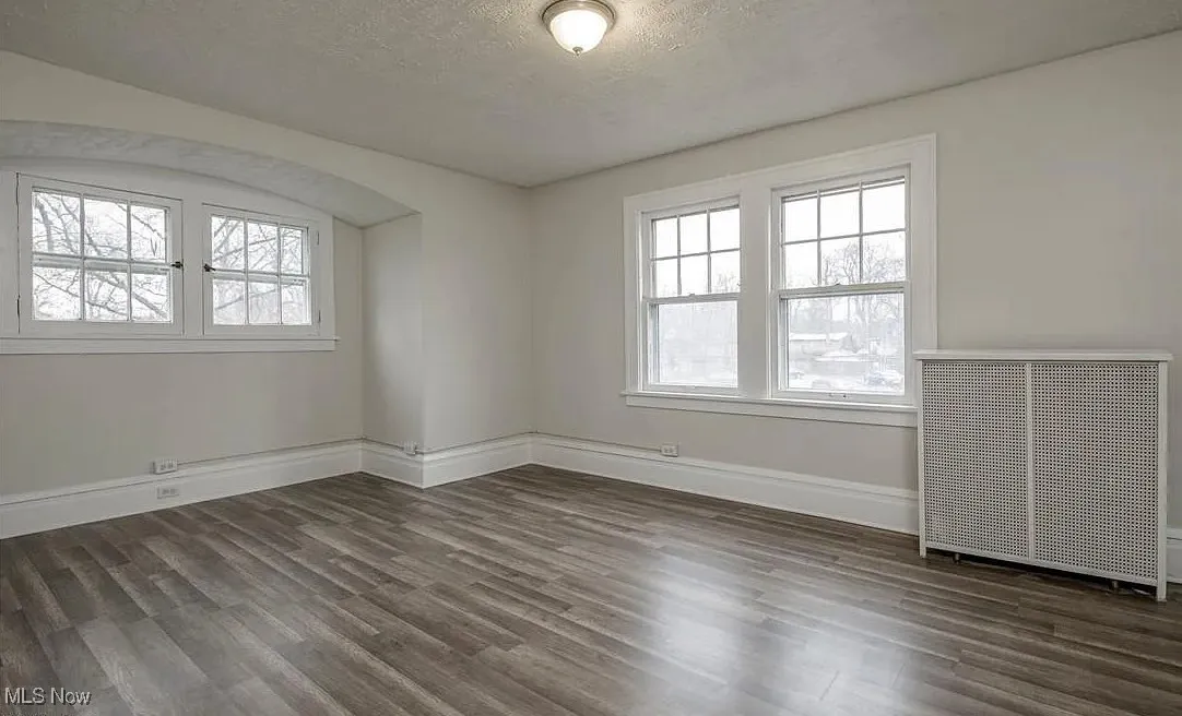 Spare room with dark wood-type flooring, a textured ceiling, and radiator