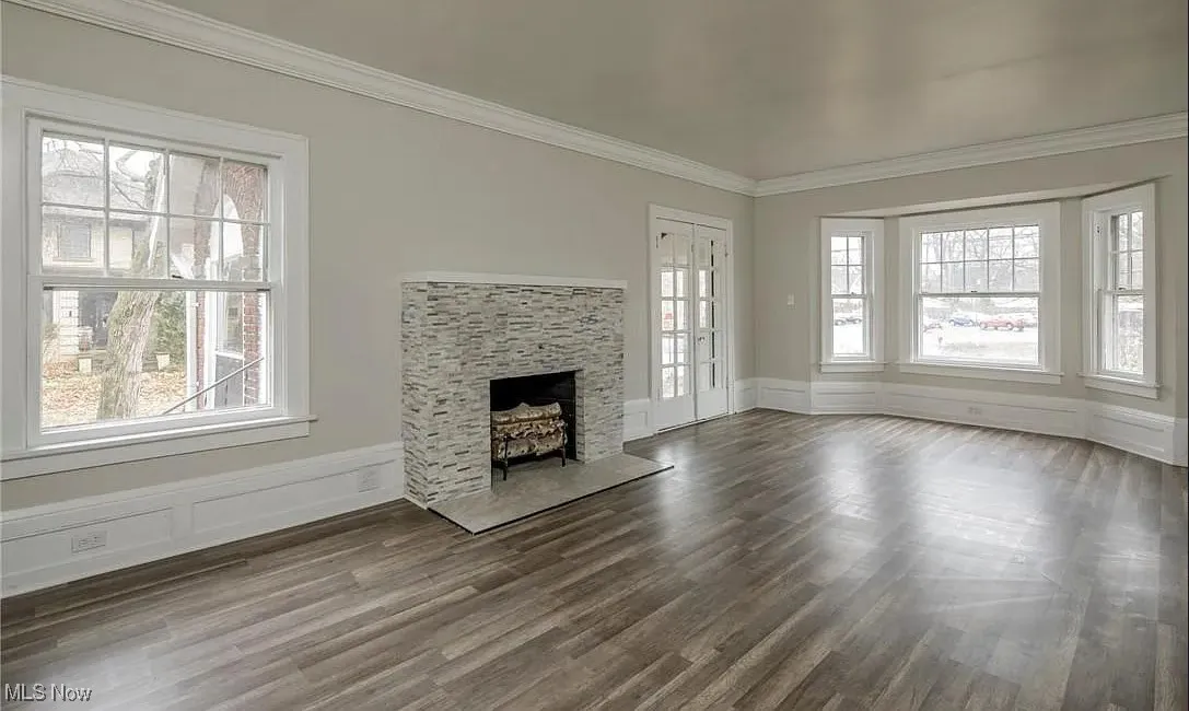 Unfurnished living room featuring crown molding, a fireplace, and wood finished floors