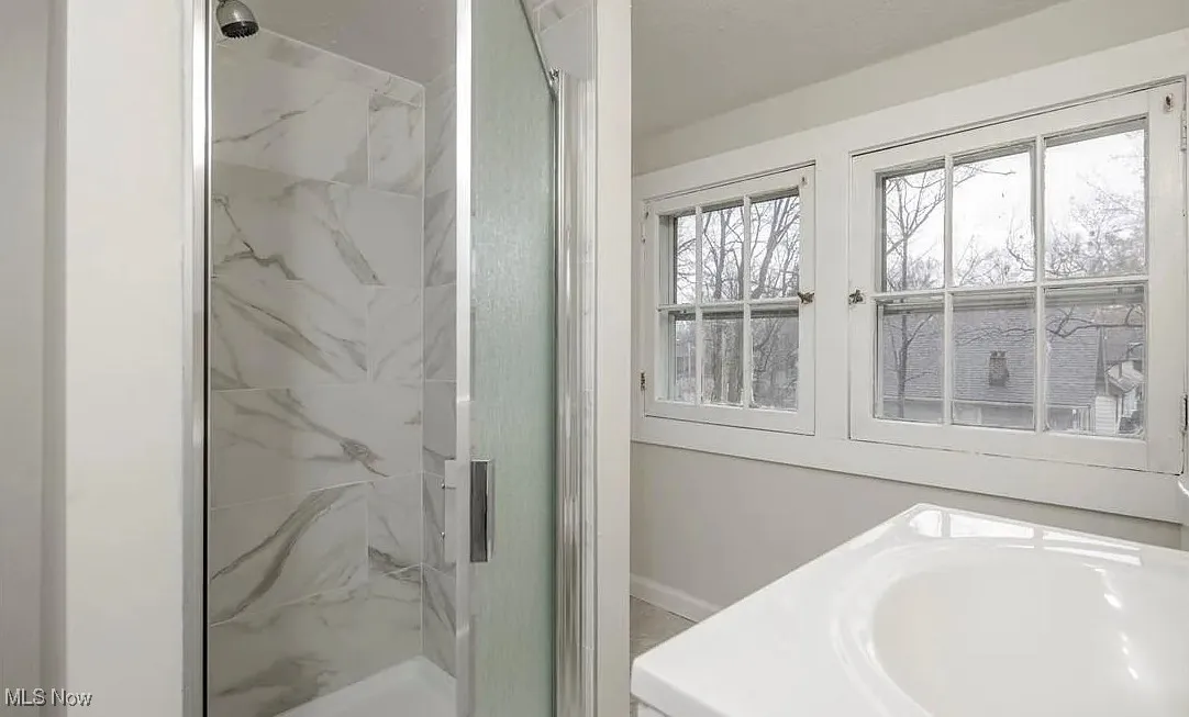 Bathroom featuring a marble finish shower and vanity