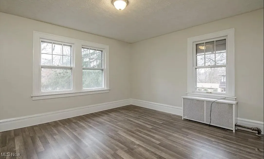 Unfurnished room with radiator heating unit, wood finished floors, and a textured ceiling