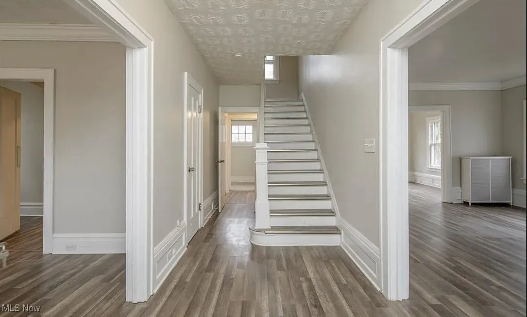 Stairway with wood finished floors and ornamental molding