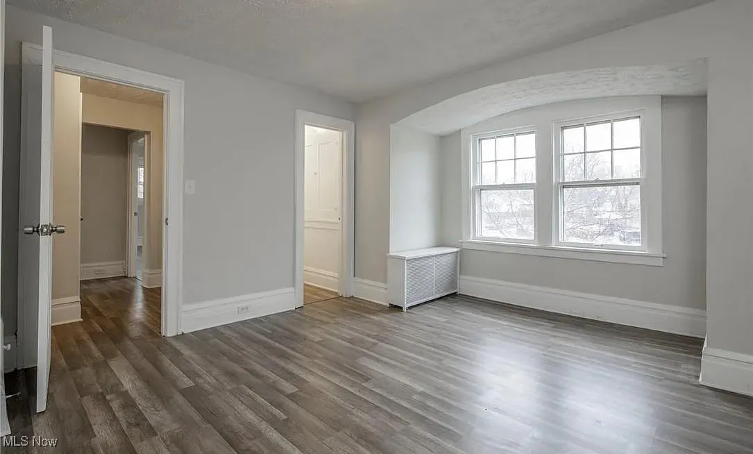 Unfurnished room with wood finished floors and radiator