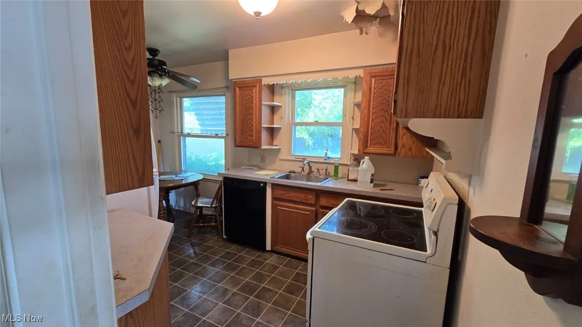 Kitchen with white range with electric stovetop, brown cabinetry, light countertops, and dishwasher
